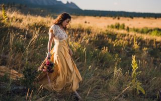 bride in a yellow dress holding elopement bouquet walking through golden grass in boulder colorado