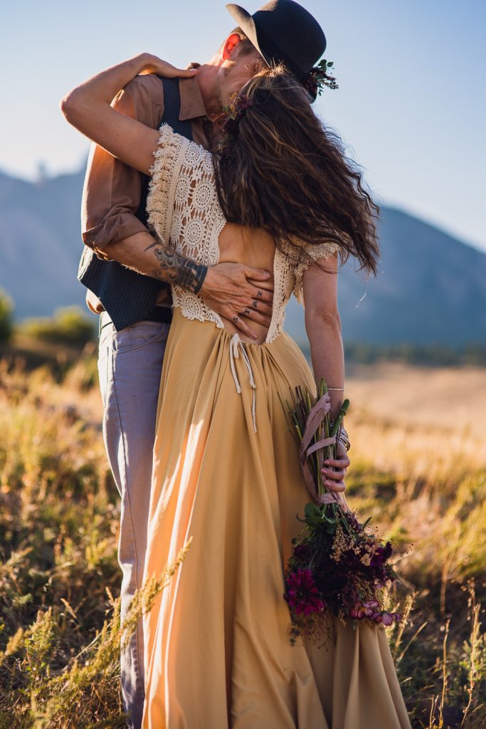 bride in yellow dress holds an autumn bouquet while embracing her groom during their colorado elopement