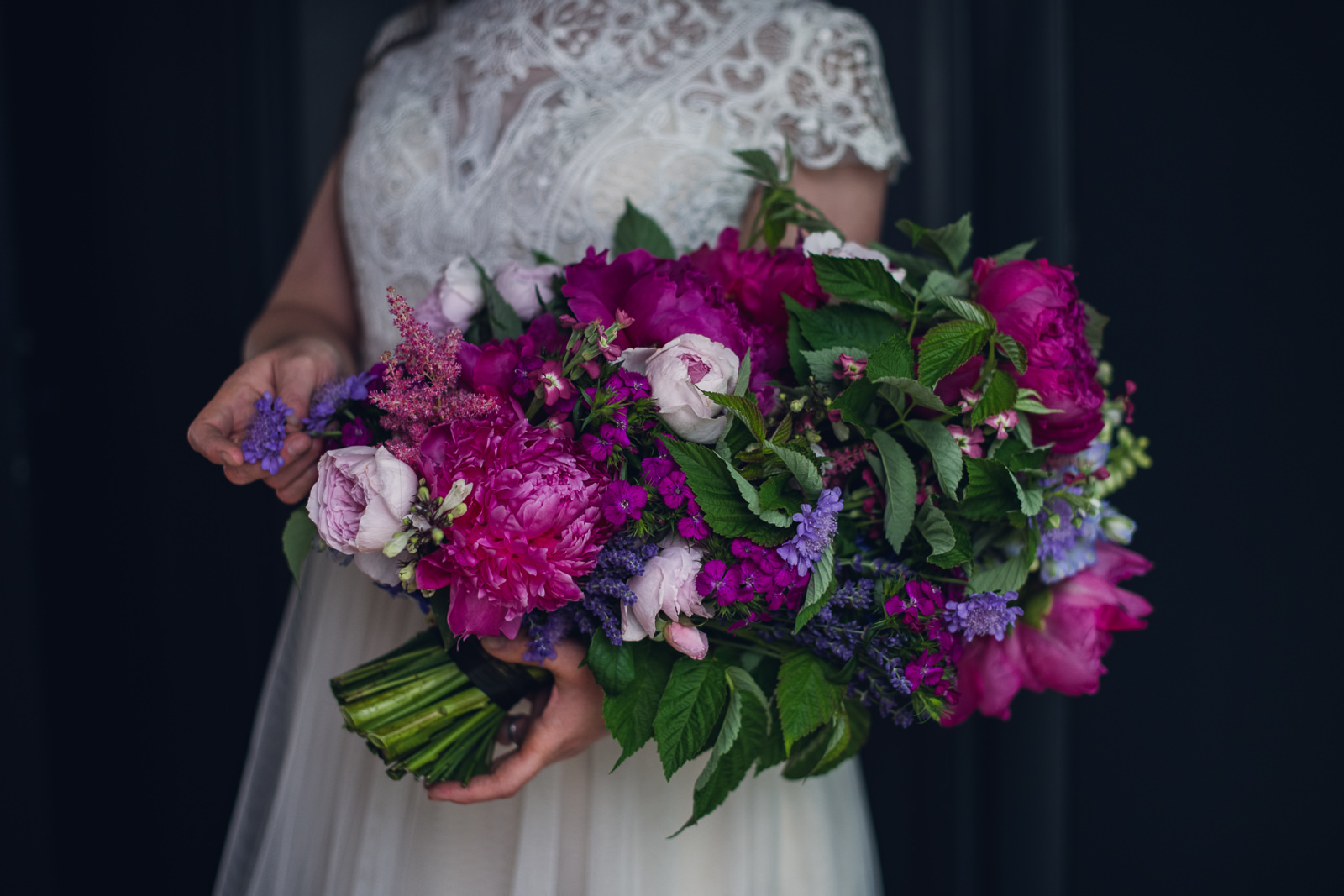 bride holding a vibrant pageant style bouquet of magenta and purple flowers