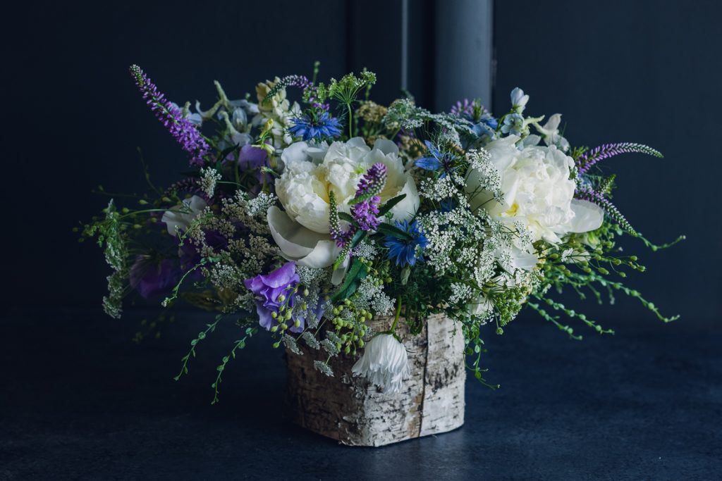 blue purple and white centerpiece in a birch box container