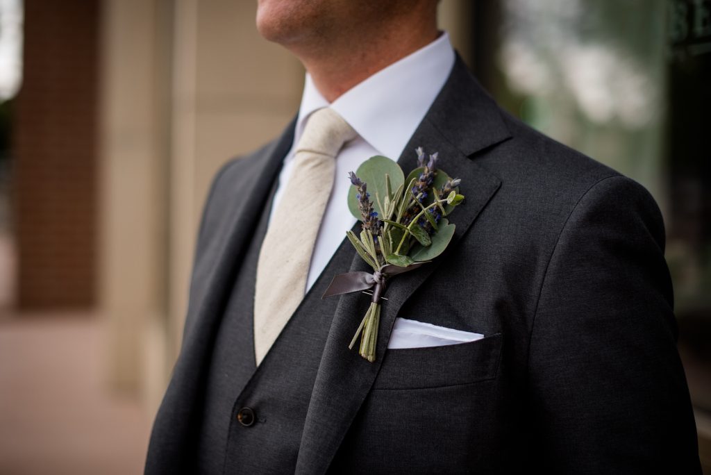groom in dark grey suit with boutonniere