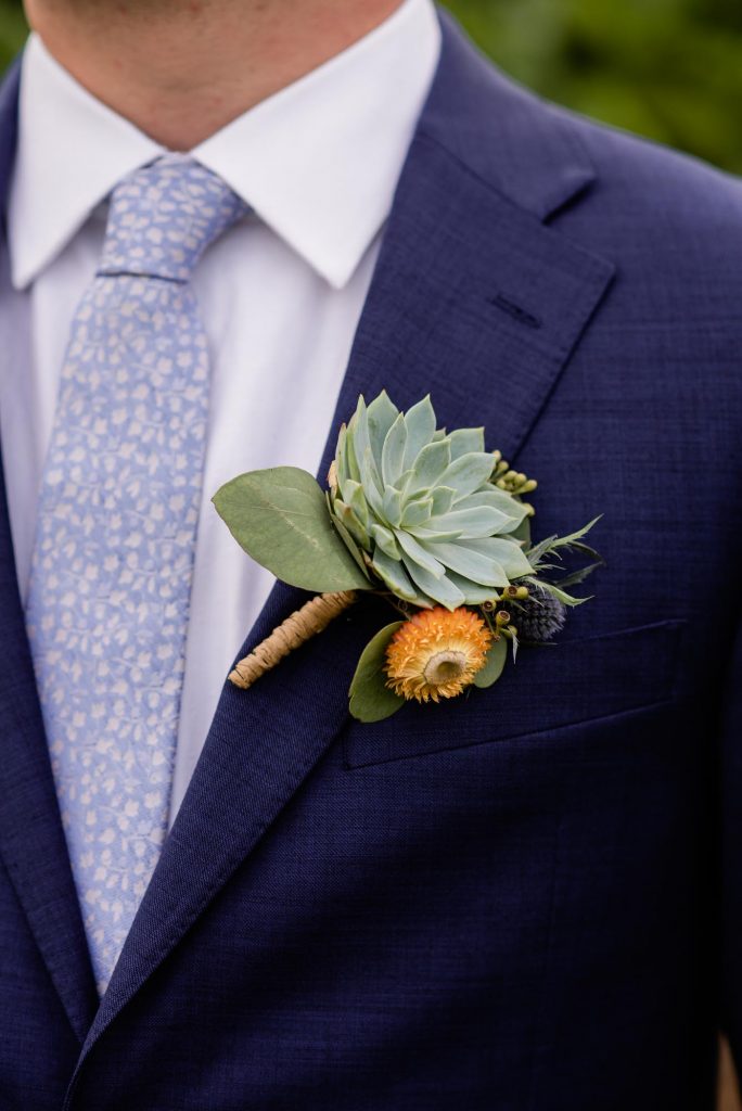 groom in a blue suit with a succulent boutonniere