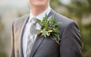 groom in grey suit with large greenery boutonnière