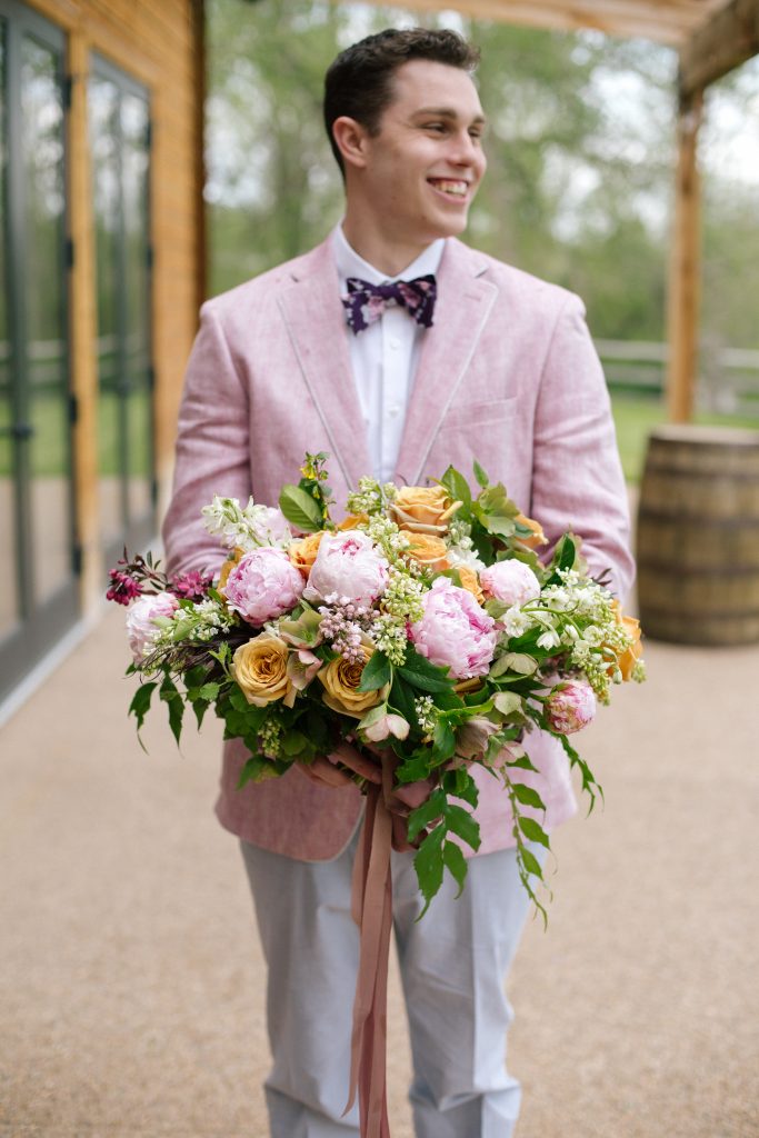 groom in pink jacket holding spring pastel bouquet