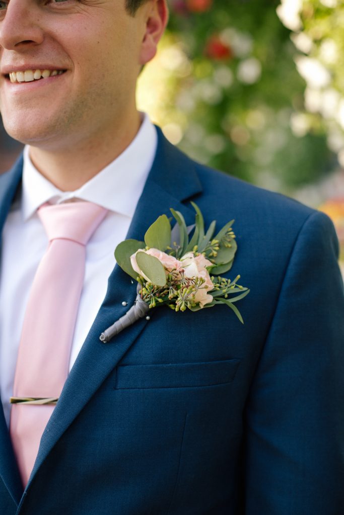 groom in a blue suit with a boutonniere