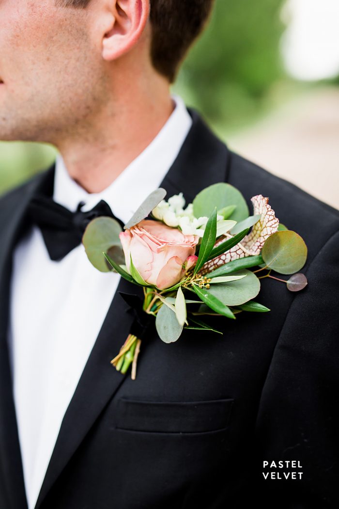 groom in black suit with large pastel boutonnière