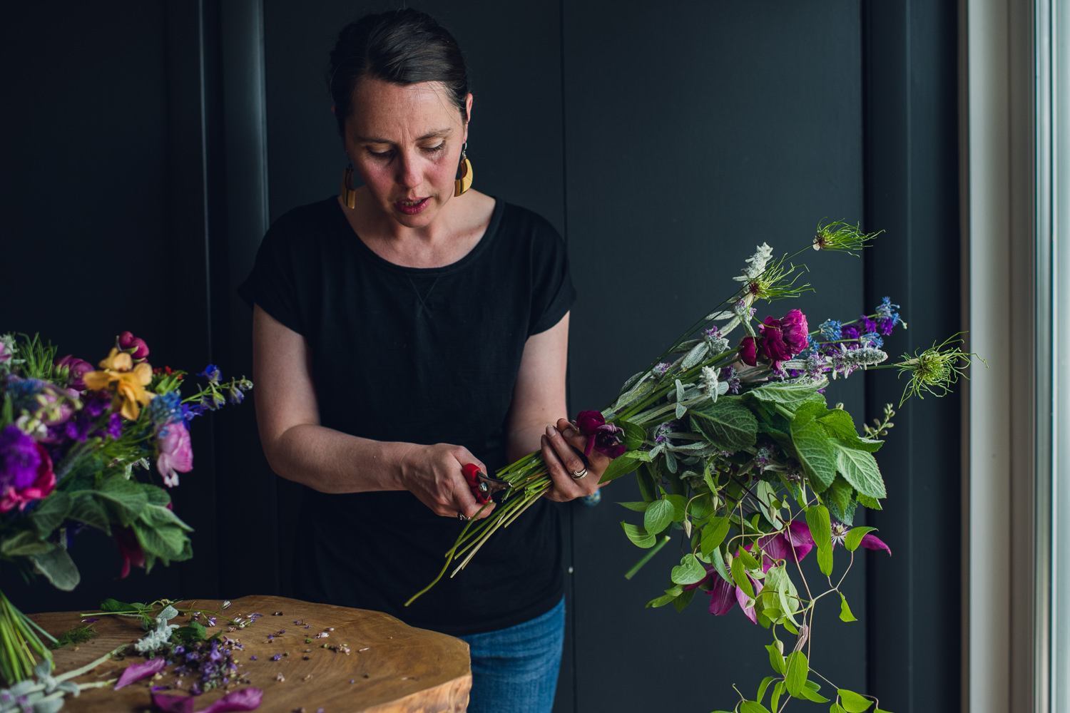 woman trimming flowers to create a vibrant bouquet