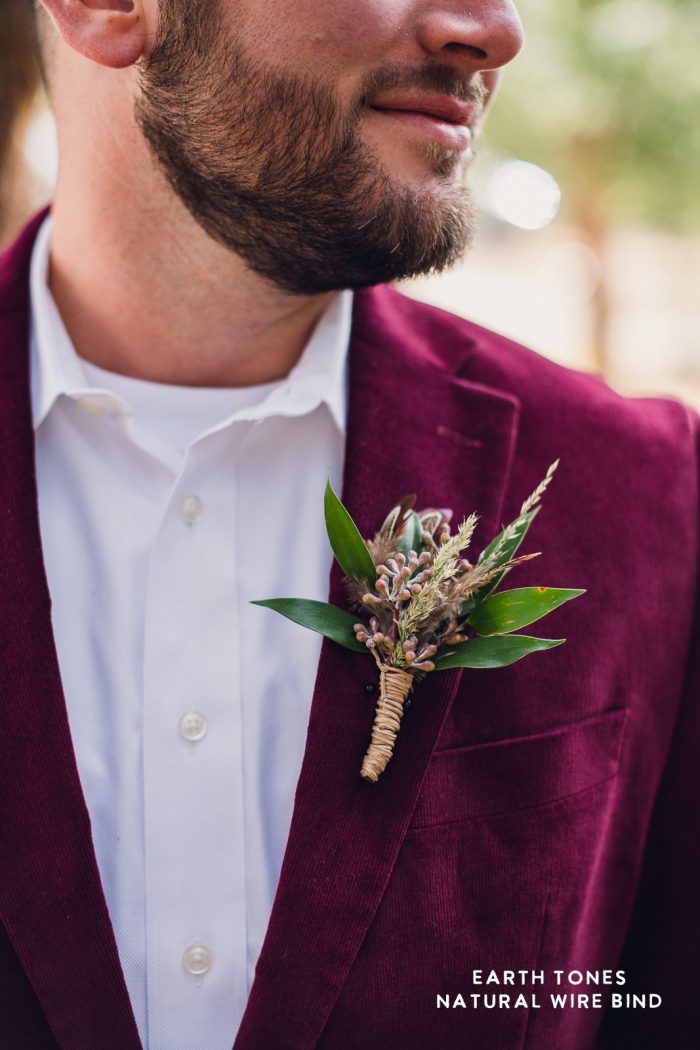 groom in maroon velvet suit wearing an earth tone boutonnière during his elopement
