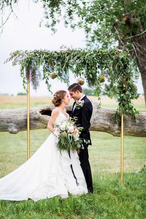couple standing in front of a greenery garland wedding ceremony arch
