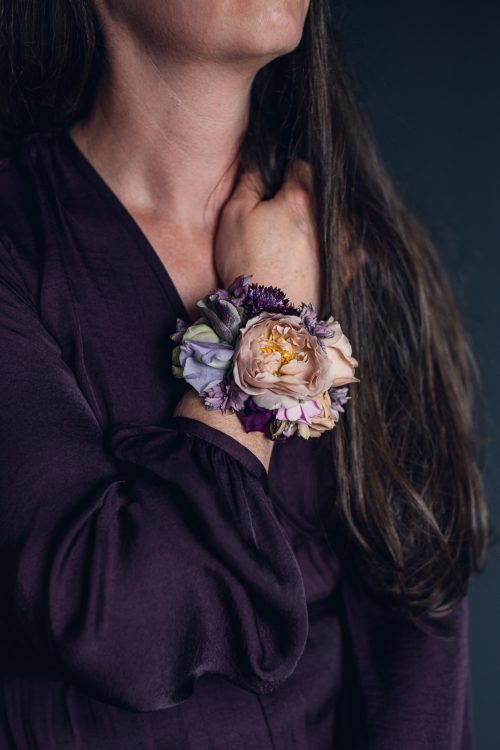 woman in purple dress wearing a floral wrist cuff corsage