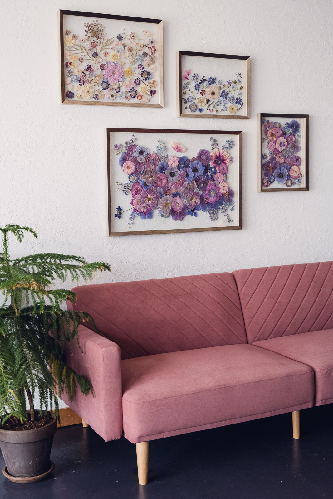 pressed flower bouquet preservation art set hanging on the wall over a rose colored couch