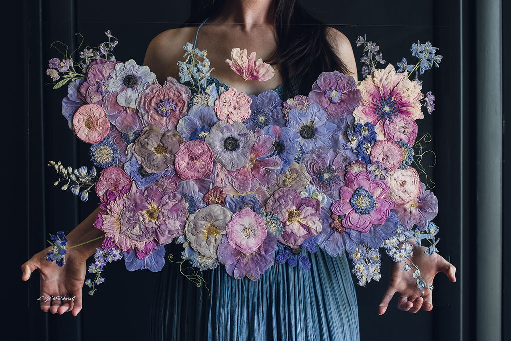 woman in blue dress holding pressed flower bouquet preservation art piece mounted on glass