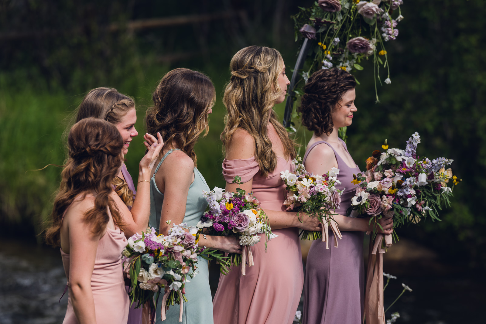 bridesmaid in mix and match pastel dresses holding bridesmaid bouquets for a wedding ceremony at the landing estes park colorado