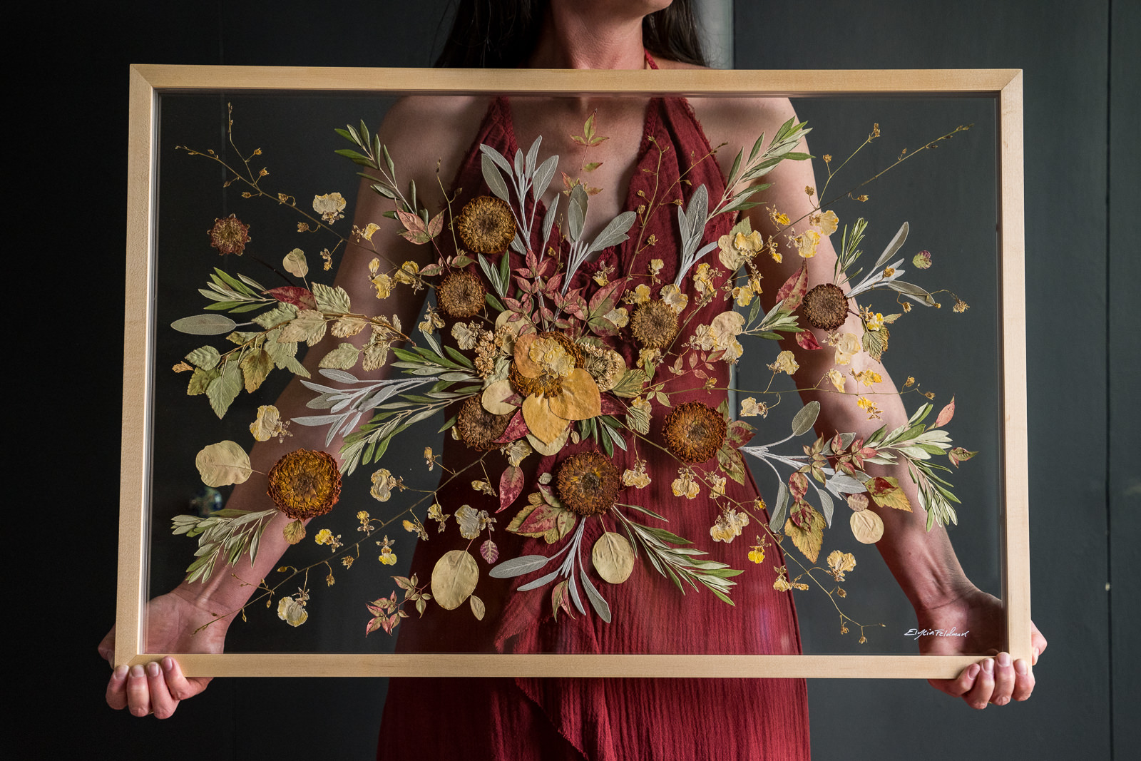 woman holding botanical pressed floral preservation art of yellows reds and browns