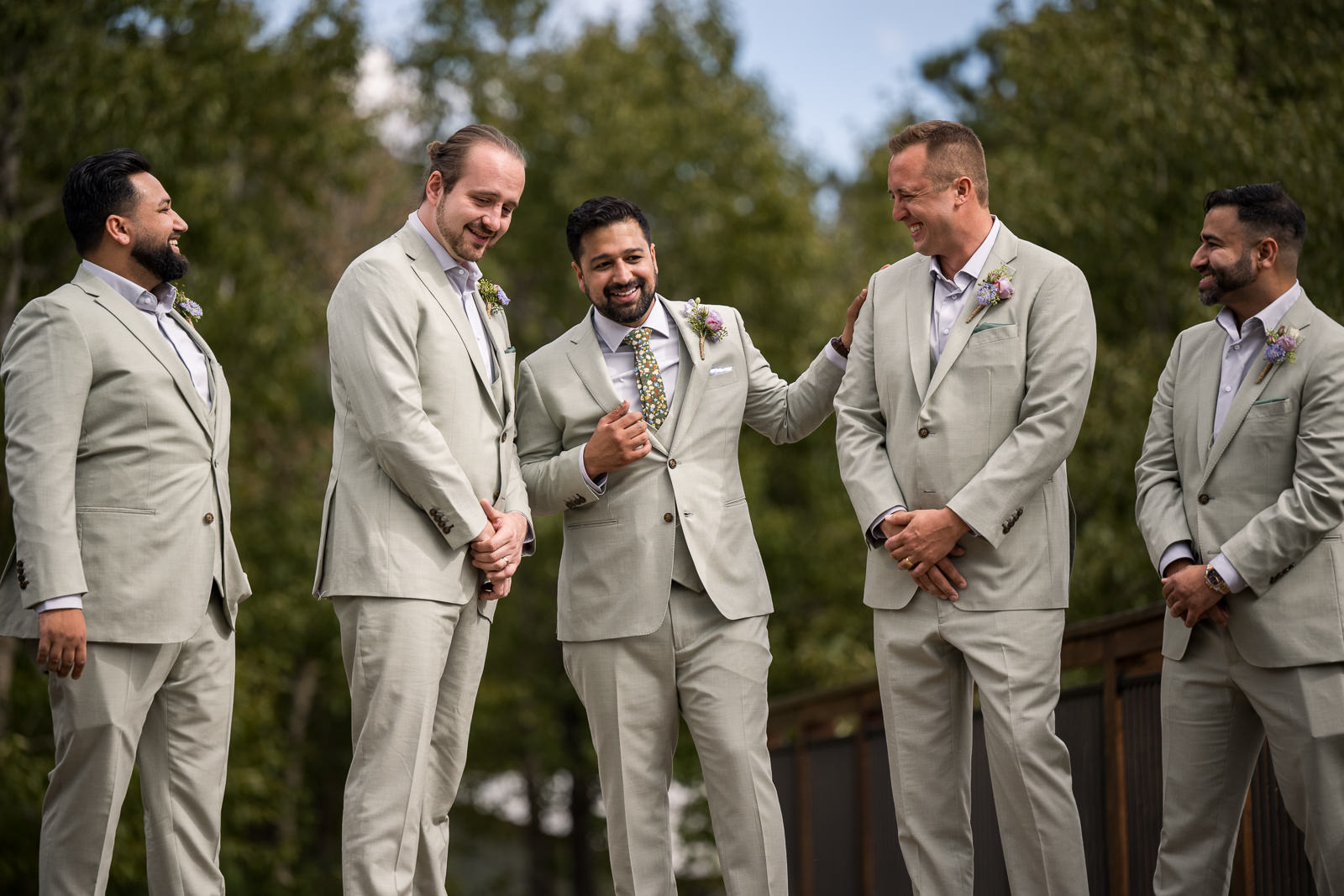groom standing with groomsmen in pale sage suits before colorado mountain wedding