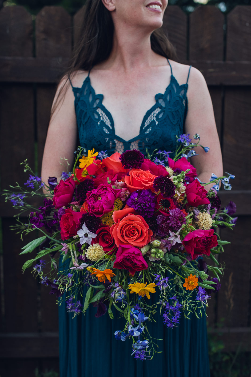 woman wearing blue free people dress holding vibrant jewel tone rainbow bridal bouquet