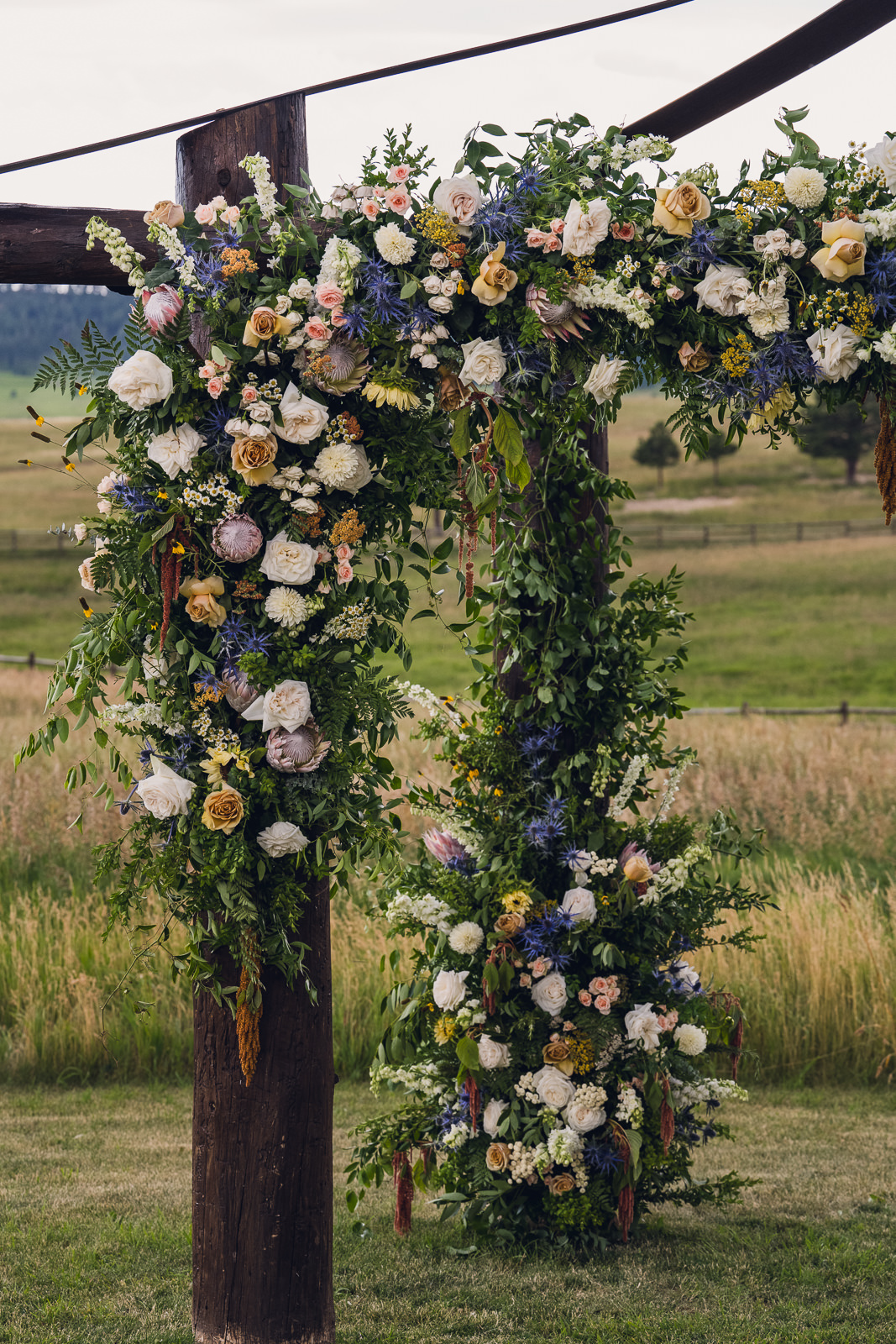 lush florals on a wooden wedding ceremony chuppah arch at spruce mountain in colorado