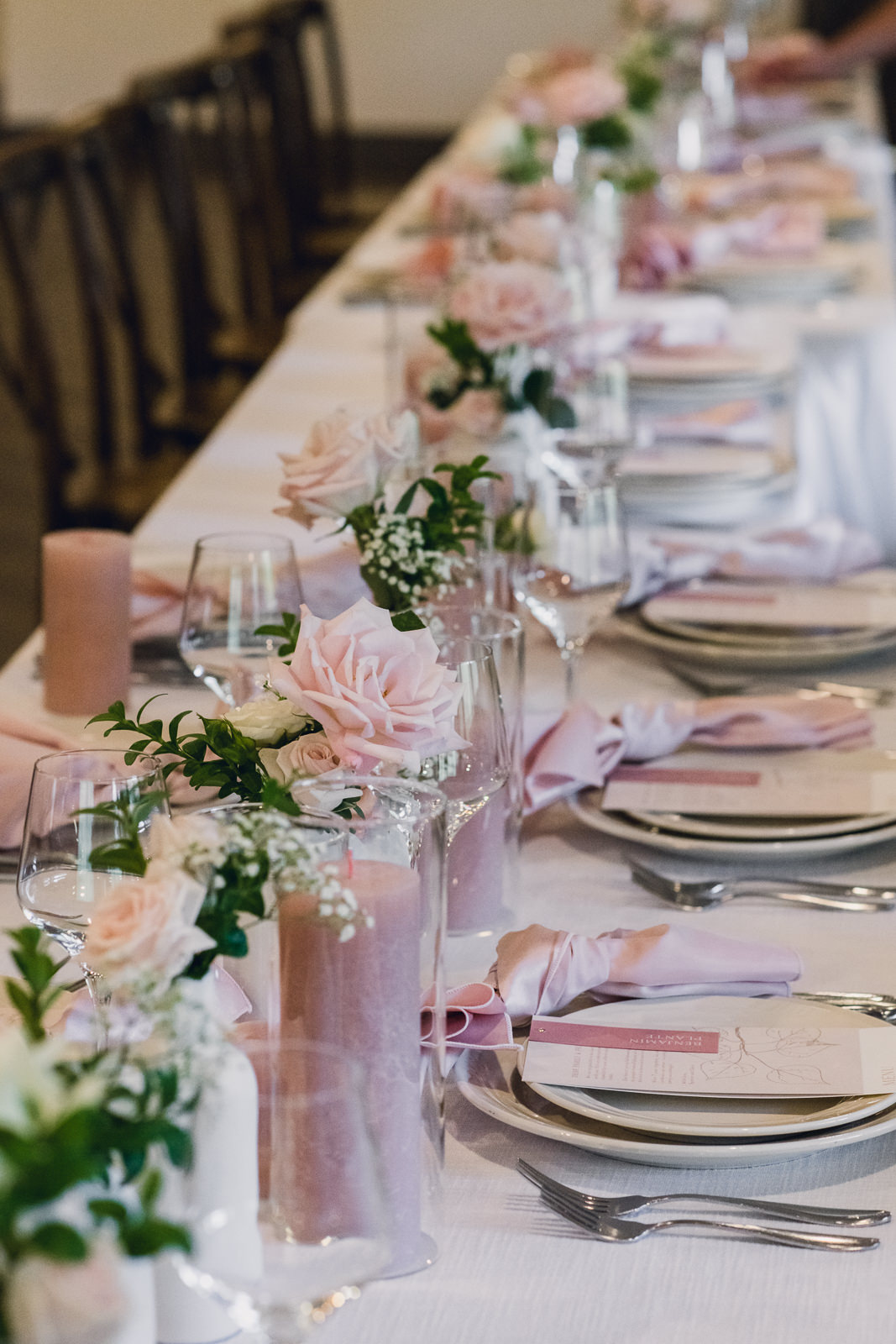 pink and white flowers in bud vases used as centerpieces on a wedding reception table